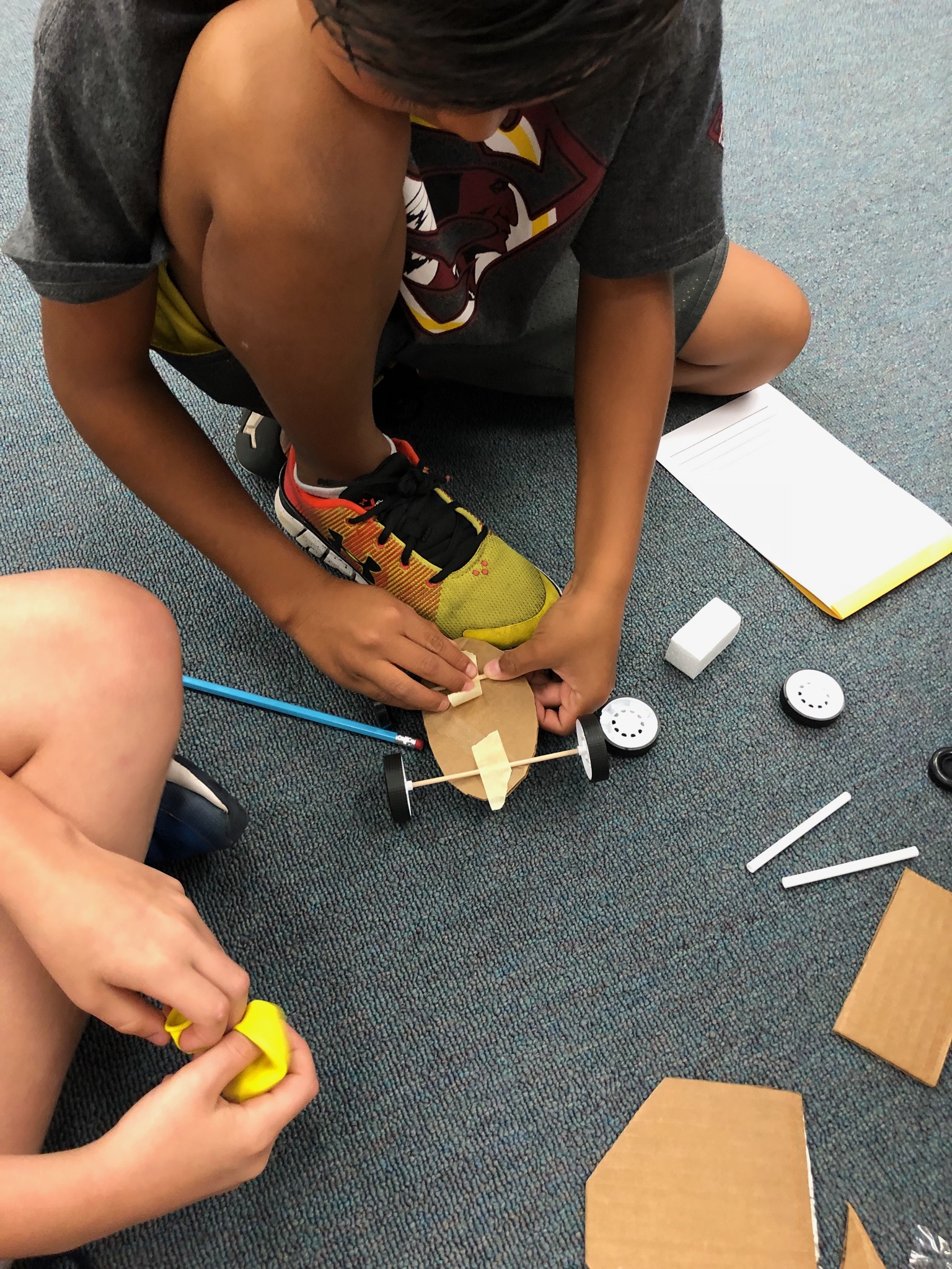 A student works on attaching his wheels to a vehicle.