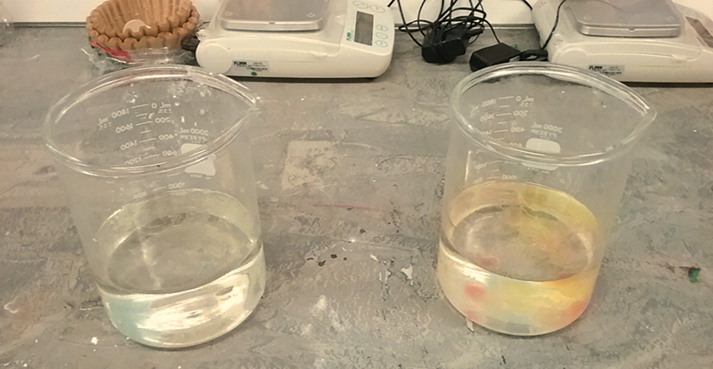 two beakers with liquid on a lab bench. Right is colored, left is not