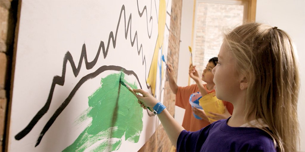 Children paint a mural after breaking down the problem into smaller parts and assigning roles.