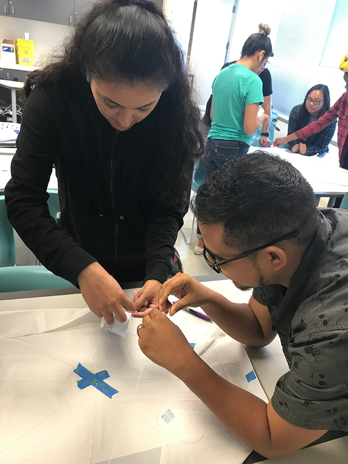 Students carefully measure and connect string from the cup, which will carry their Eggstronaut, to their parachute.