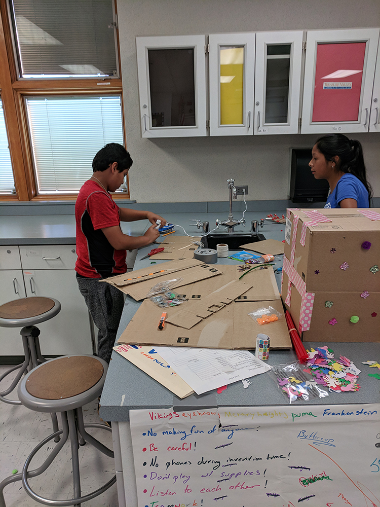 Two campers build a prototype of their invention using cardboard and duct tape.