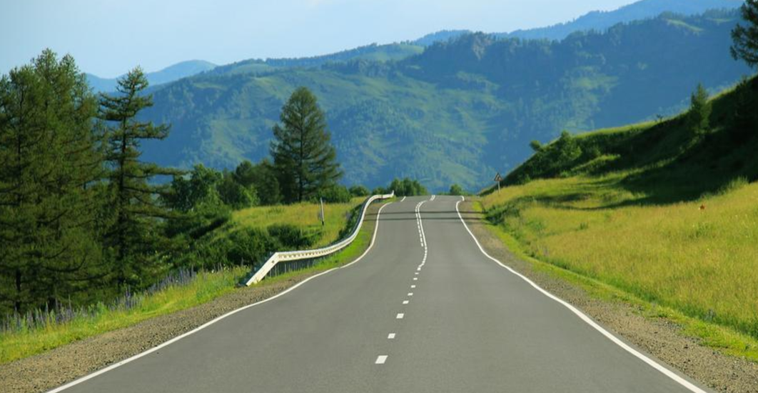 Asphalt Road with Mountains and Trees Around It on a Sunny Day