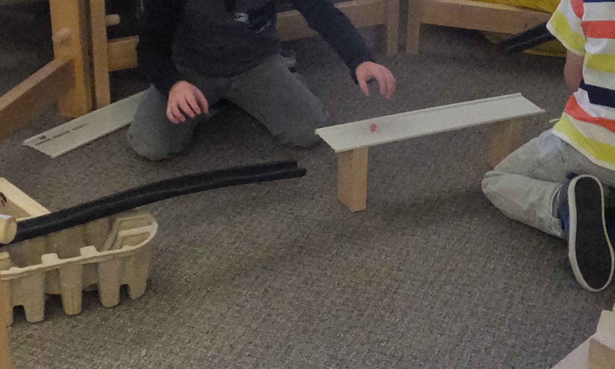 Children work on a discontinuous marble run, switching surface types.