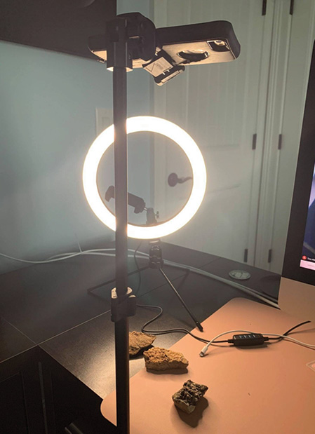 |	Figure 1: A ring light is placed on the desk, a cell phone tripod holds the phone in the downward position, then the camera app is used. 