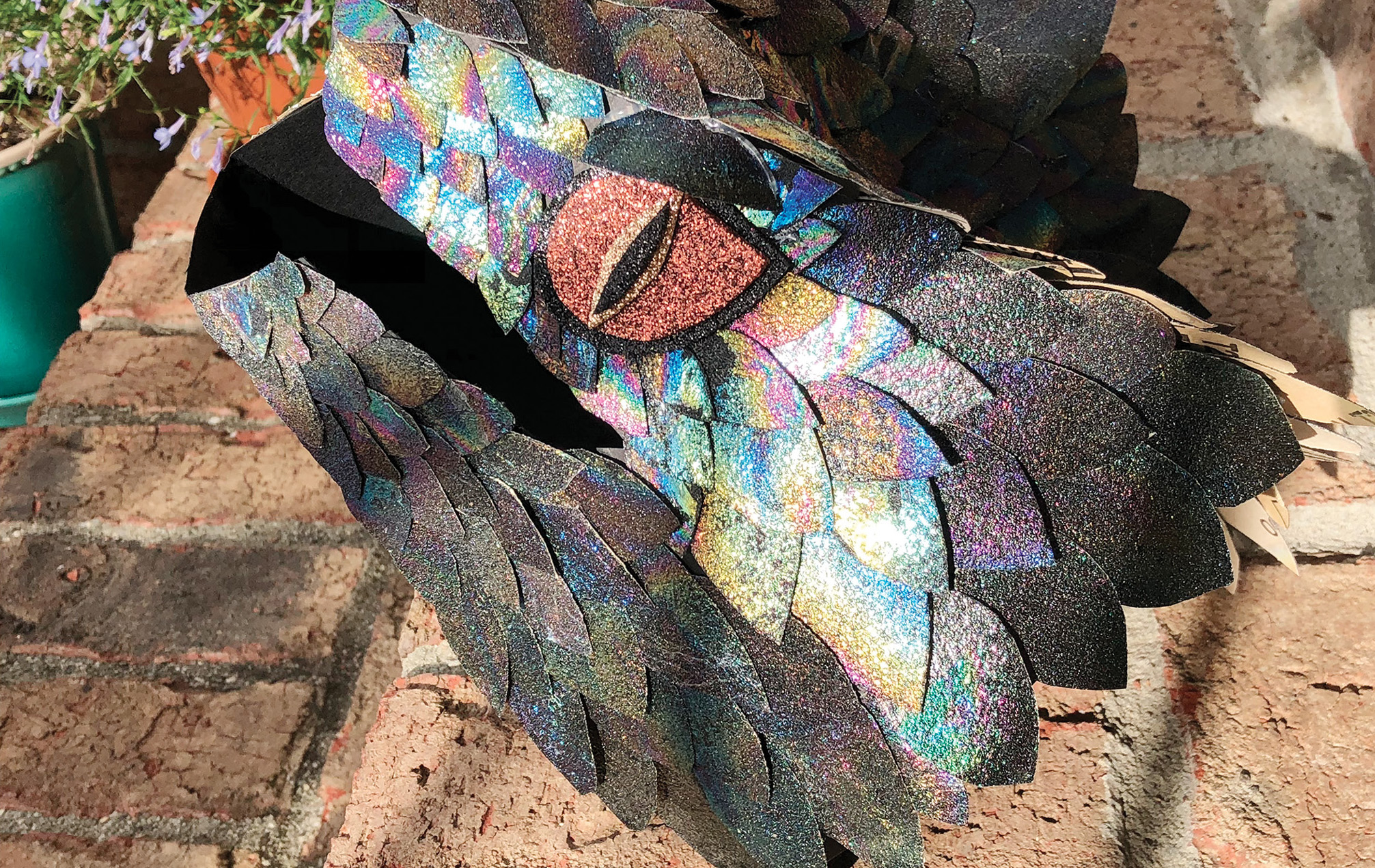 An example of an advanced art project using iridescent scales created with sandpaper and clear nail polish thin films. The eye of this dragon was made with glitter foam paper, and the frame was simply an origami dragon head shaped using black matting paper.