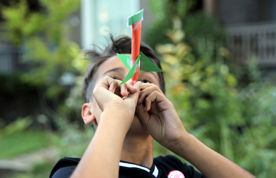 A student demonstrates his straw and paper airplane launcher.