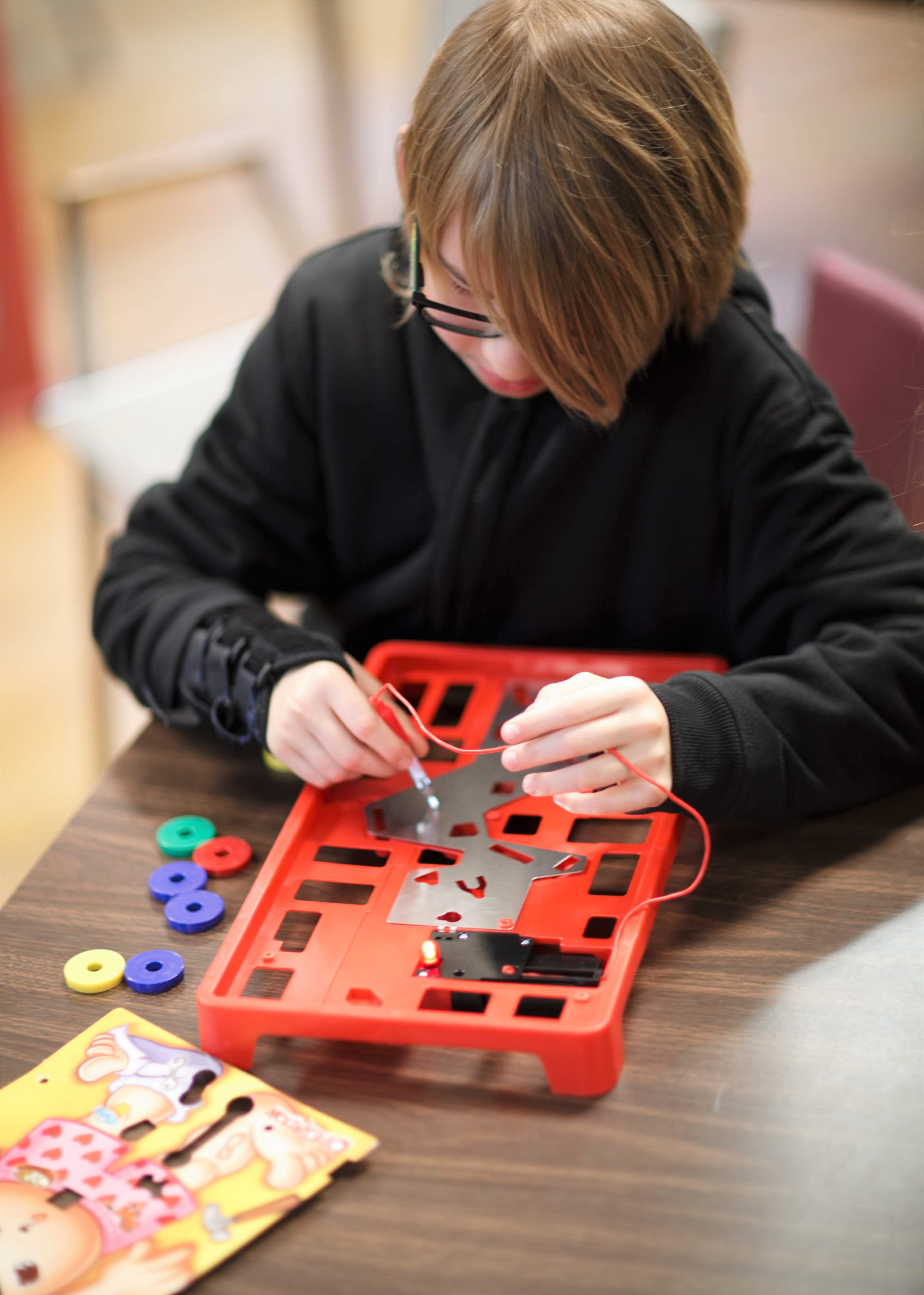 Workshop participant dismantling an operation game to understand how circuits work.