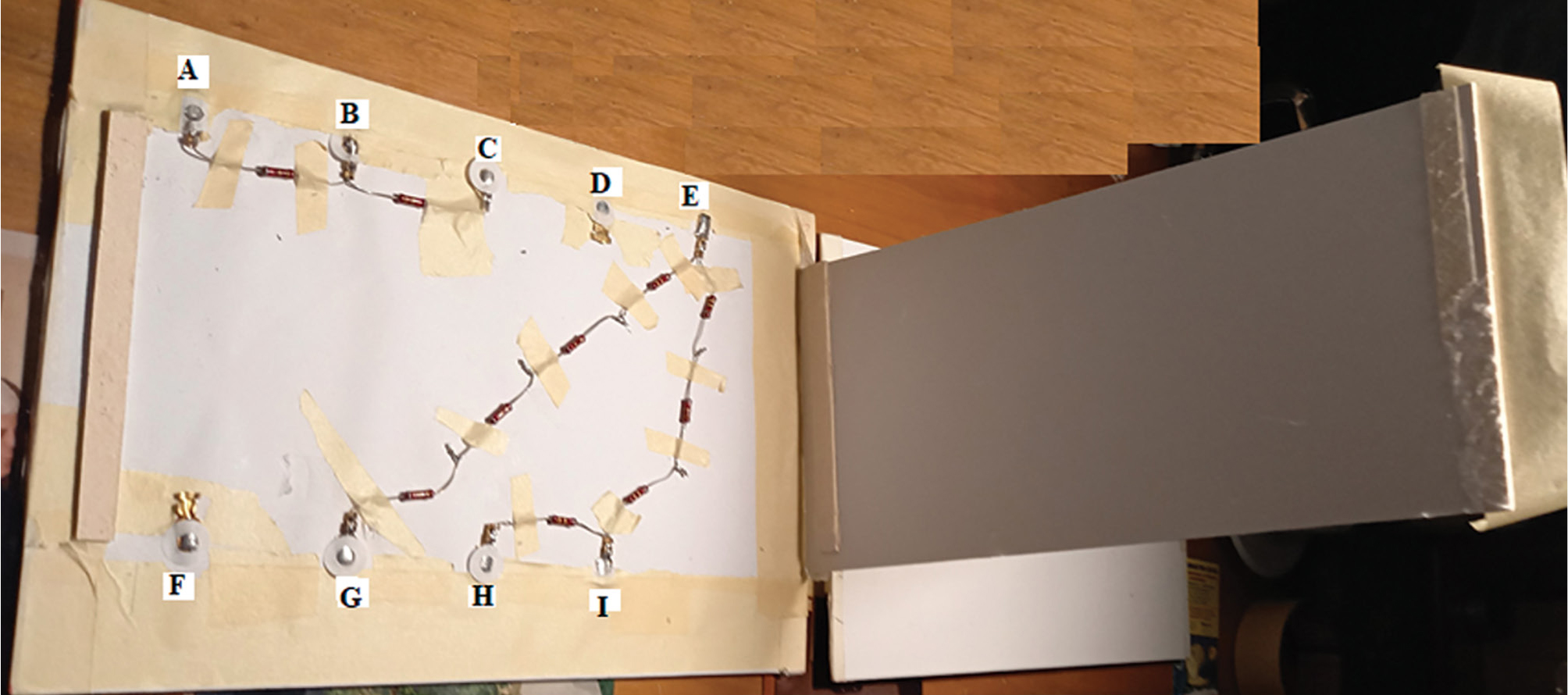 Black Box construction instructions. To construct the Black Box, we used 8.2Ω, 1W resistors, tolerance 5%. Using an ohmmeter, we chose among the ones we bought those that reach the value 8.2Ω. Resistors are connected to each other using an electric soldering iron. The electric circuit is attached to a foam board, using tape. Then, it is closed with a properly cut piece of the foam board, which is laid on supports, as seen in the Figure below. The final shape is shown in Figure 1. The points A, B, etc. shown