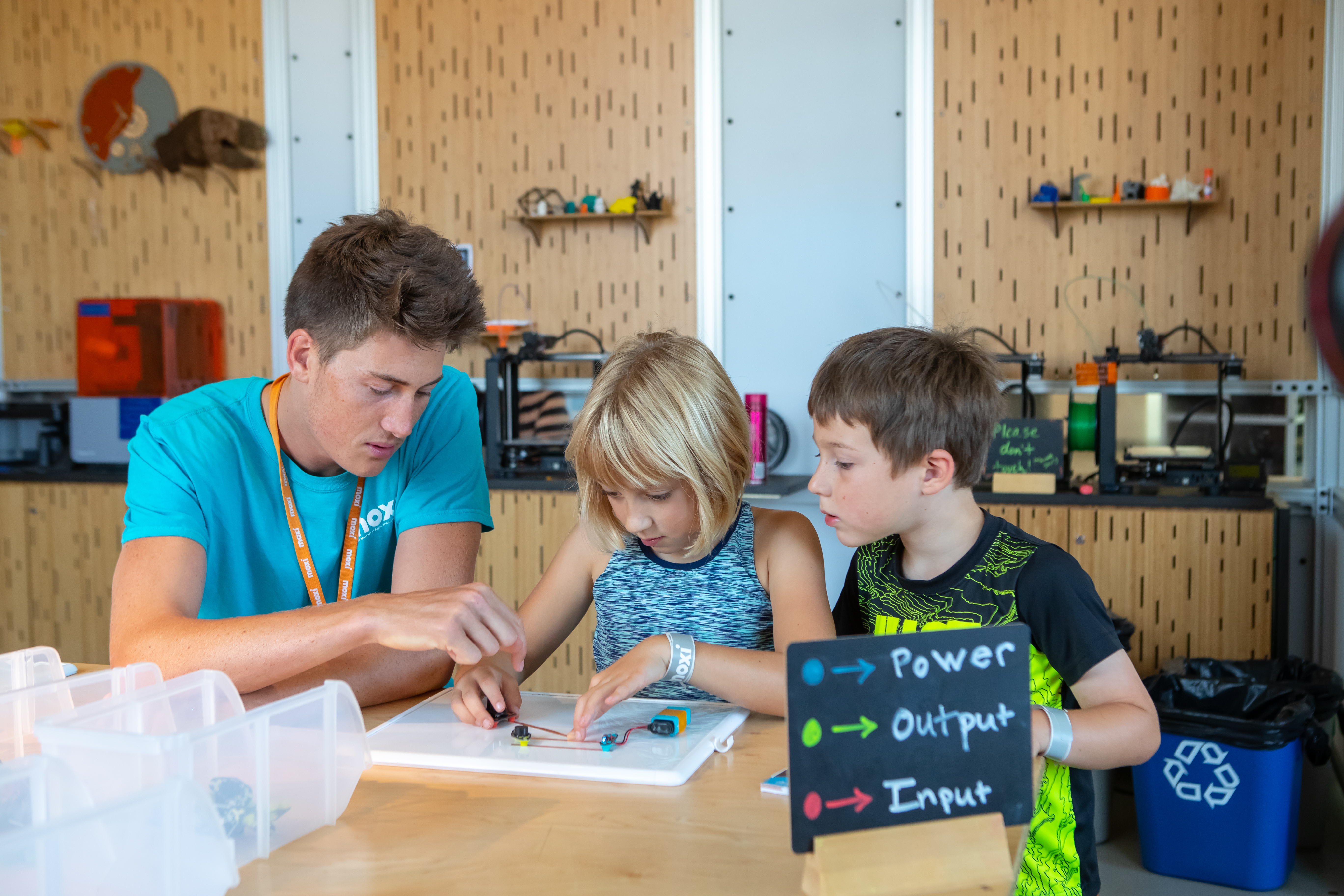 A MOXI educator engages children in designing and testing an electrical circuit.