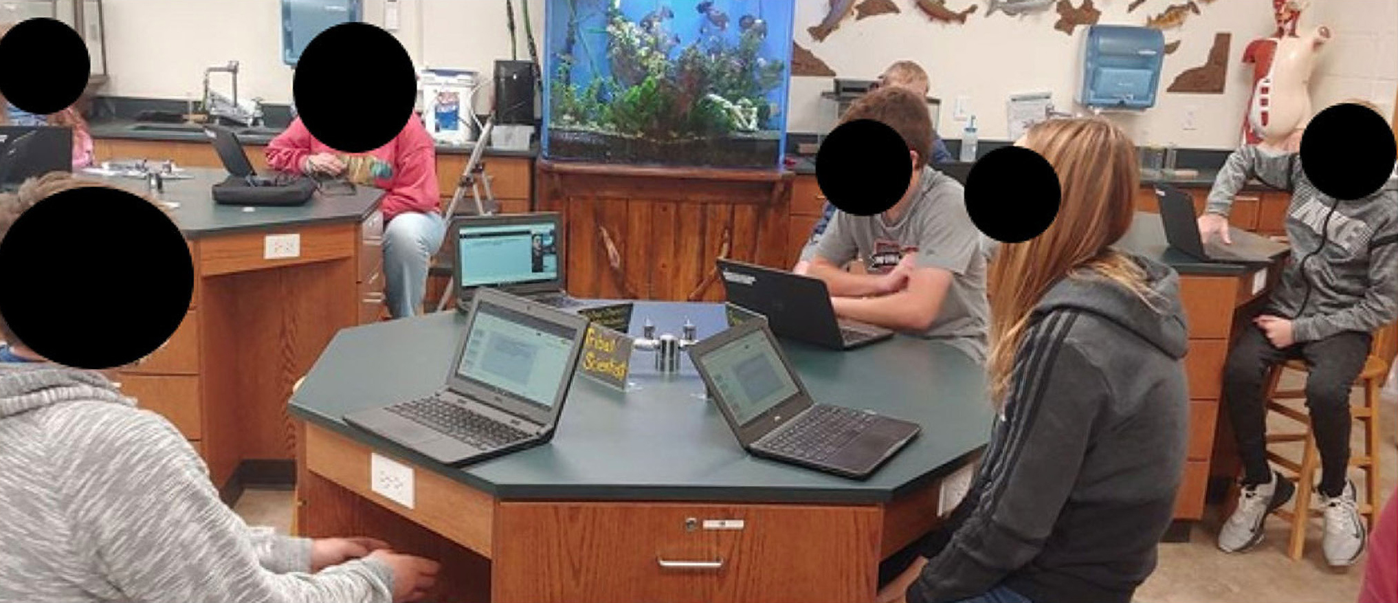 Classroom photo of pinwheel discussion showing one remote student and three in-person students during the COVID-19 pandemic.