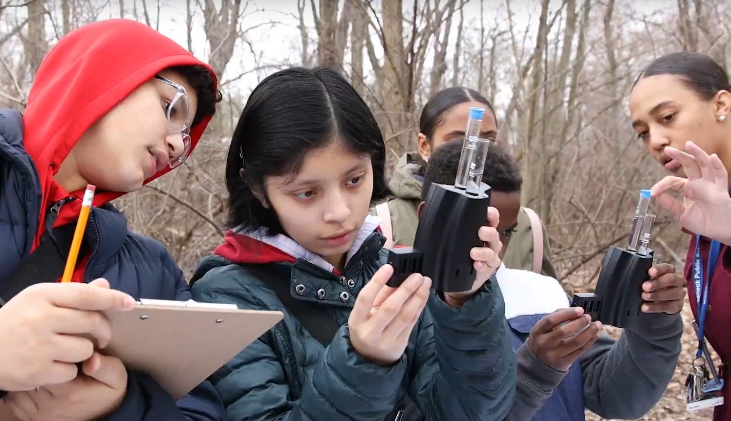 A group of seventh-grade students from Benjamin Franklin Middle School take and record measurements on water quality metrics during a class trip in spring of 2020. A science teacher on the trip, Veronica Lopez, helps students read the water quality measurements.