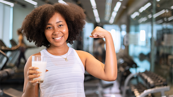 young girl drinking milk in gym after workout
