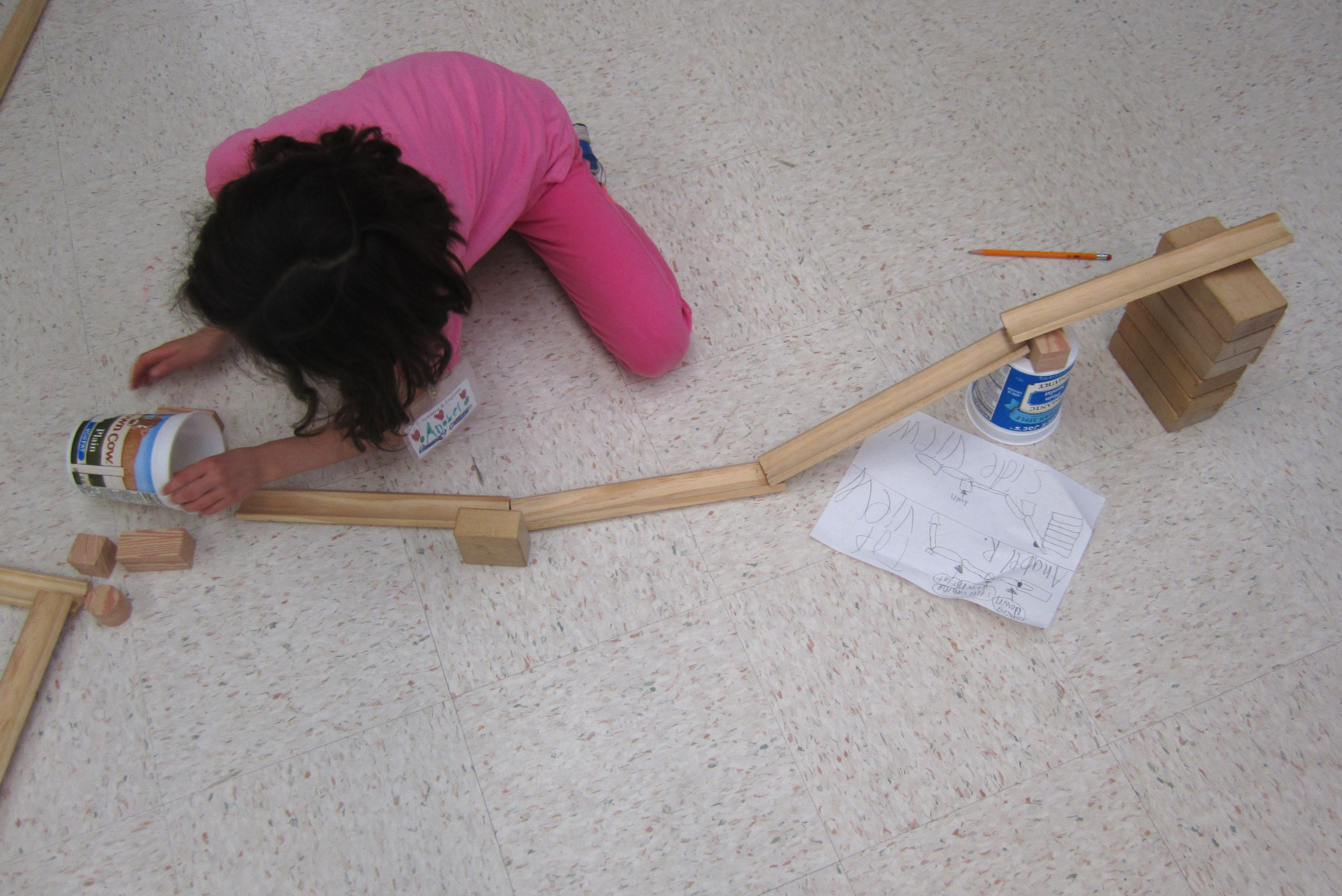 Child builds a ramp structure based on her drawing.