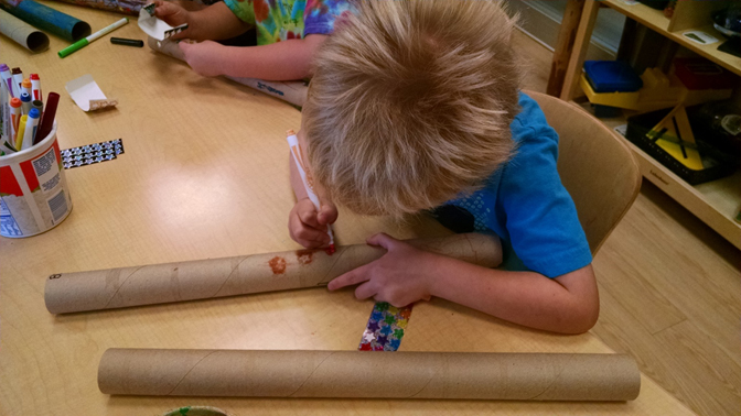 Child drawing on a cardboard tube