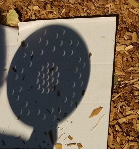 Solar eclipse image viewed on paper, projected through a colander