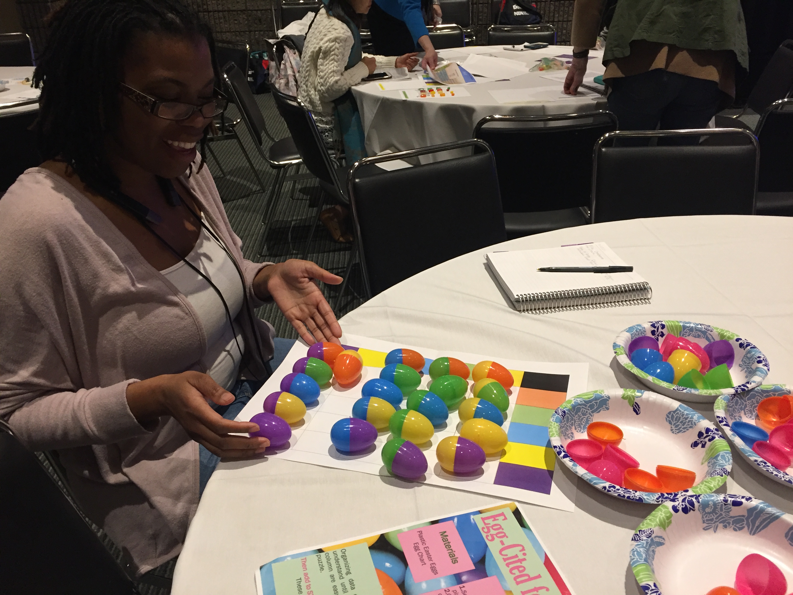 A participant trying an activity to teach children about making and using charts--a page with colored blocks on the x and y axes and plastic eggs to match with those colors.