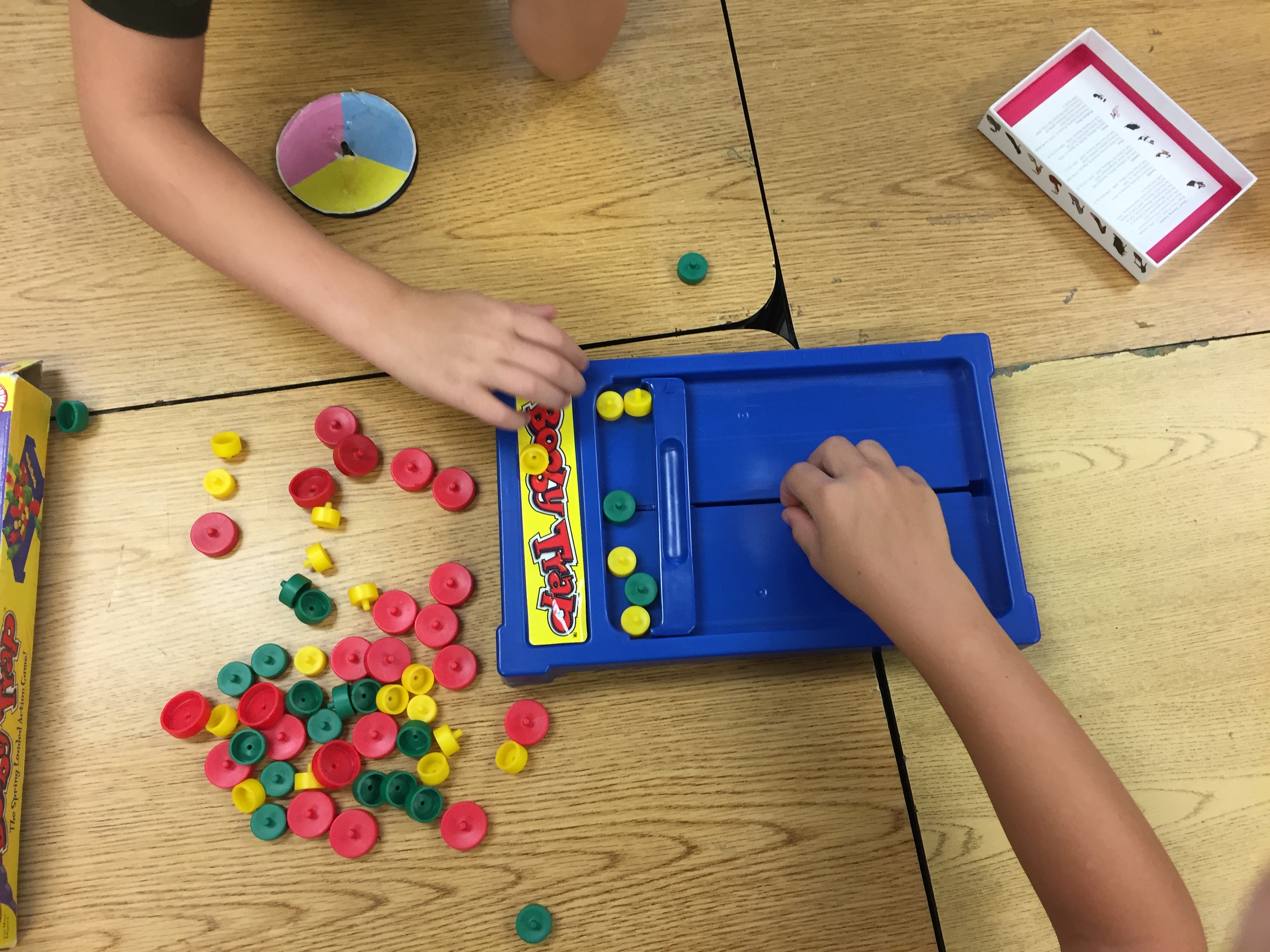 1st graders play a "Booby Trap" game, removing different size round pieces one-by-one without upsetting the board.