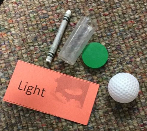 Four objects labeled "Light": a crayon, marker cap, bottle lid, hollow plastic ball.
