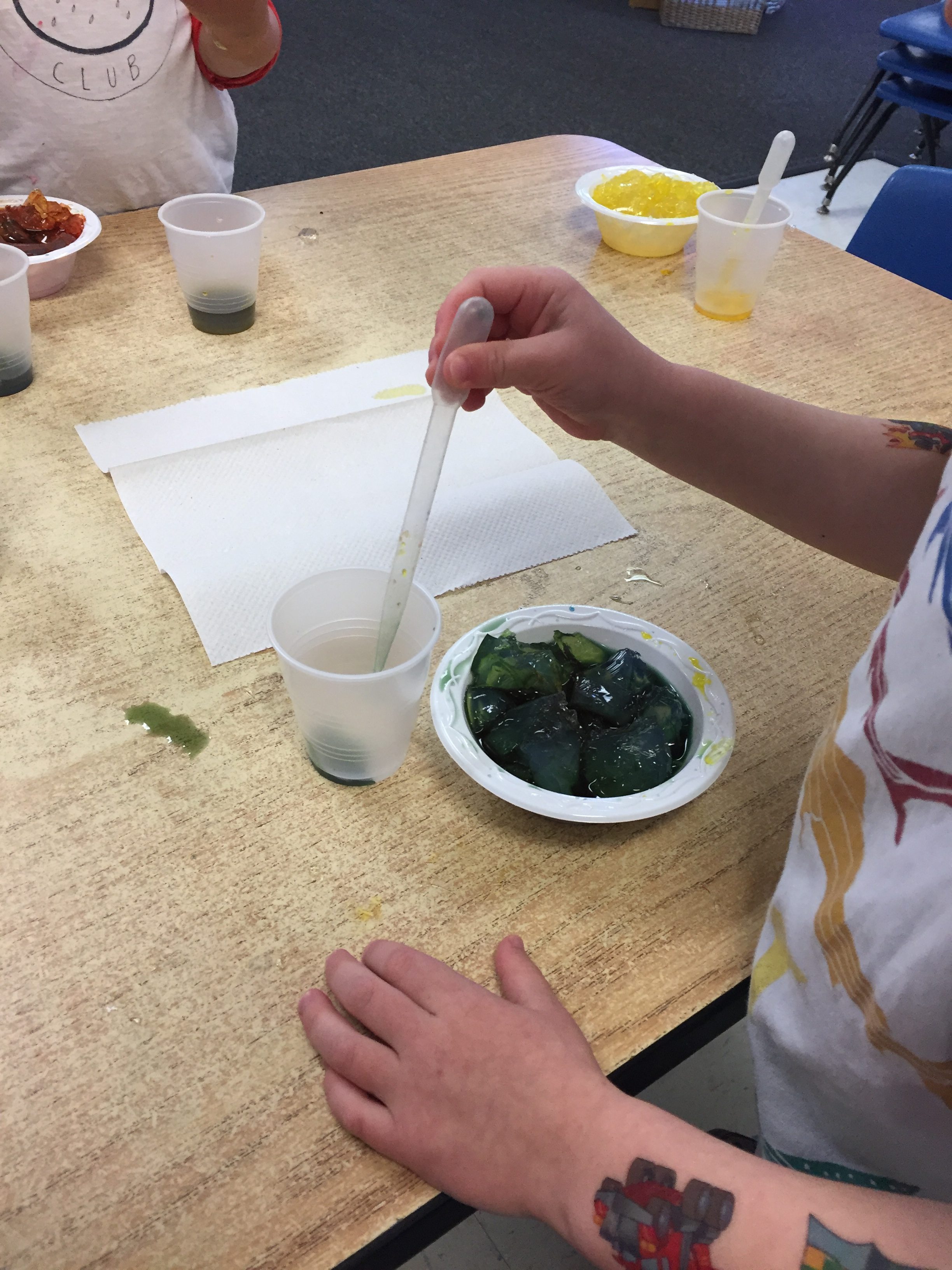 Child squirts colored water into solidified clear gelatin.