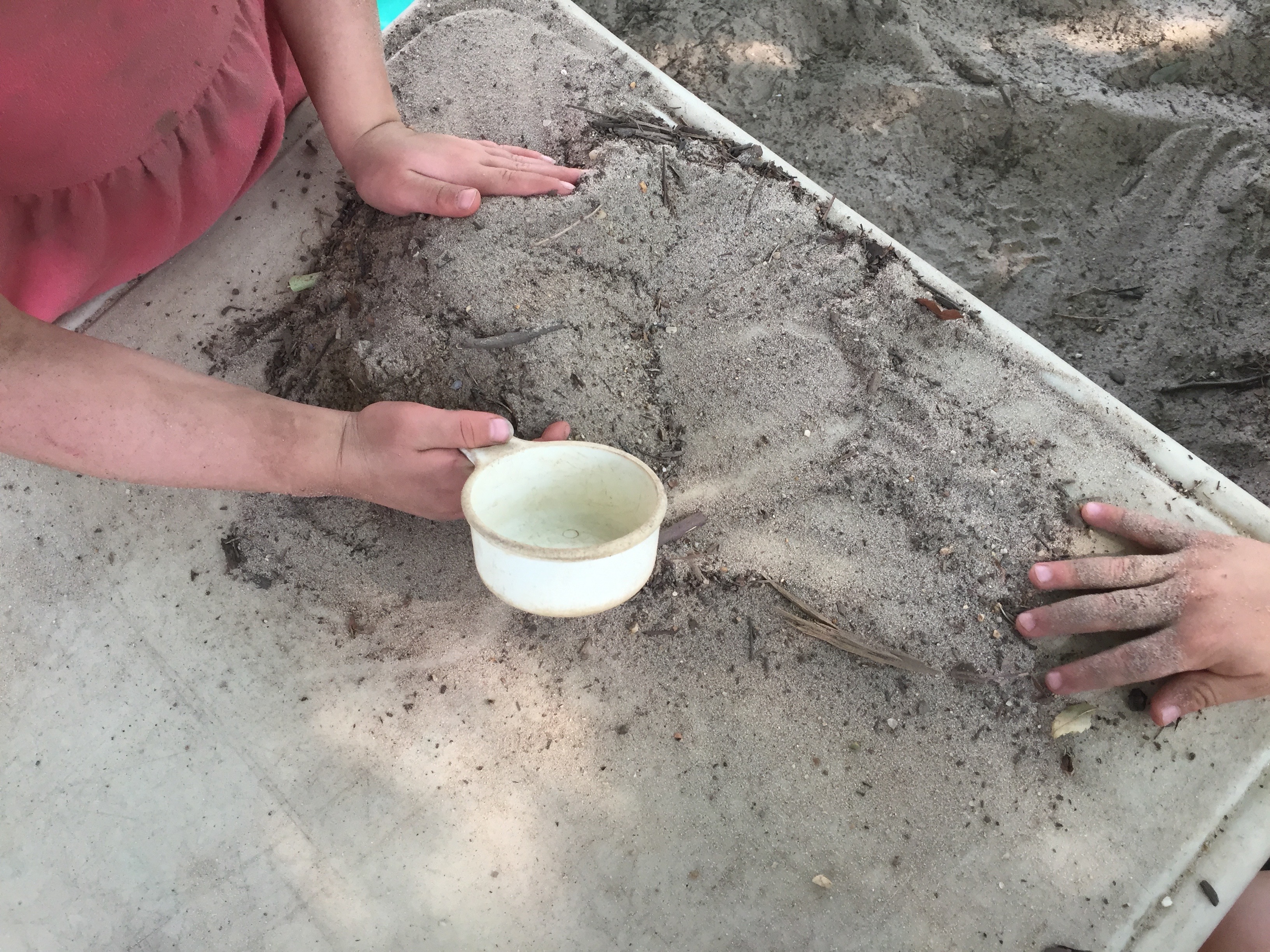 Children's hands piling up dry sand.