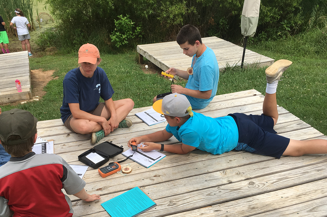 Dragonfly Detectives in a summer camp program collect weather data while their campmates count dragonflies at the pond.