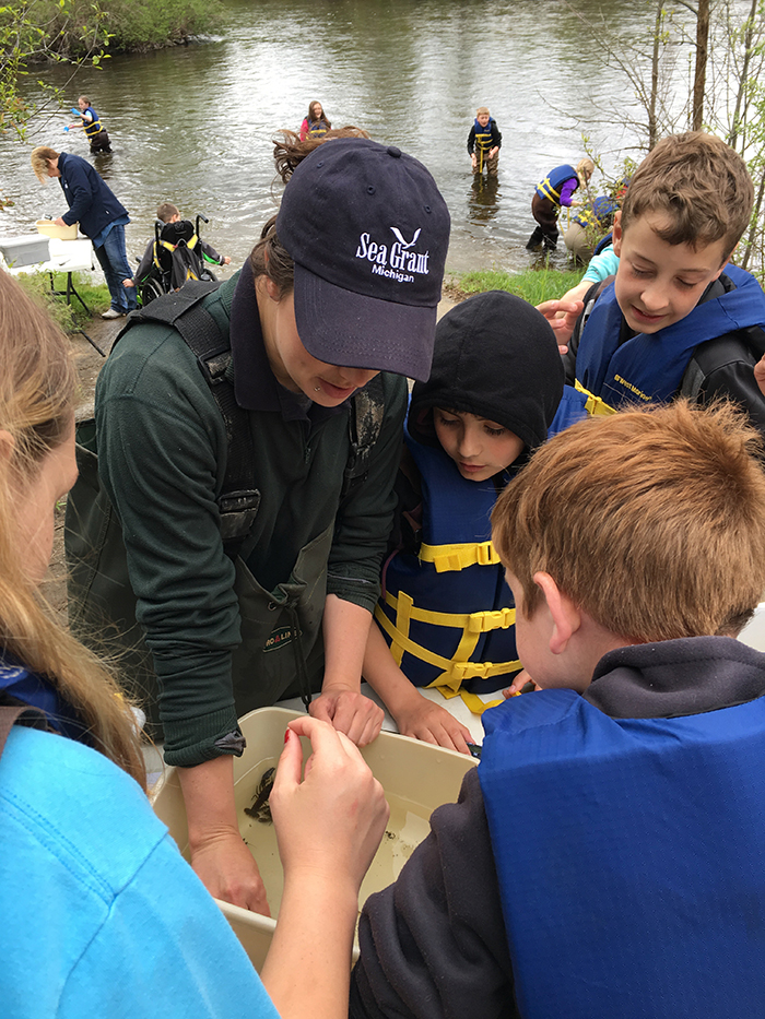 Students and community partners take samples in the Thunder Bay River to monitor for invasive species and microplastics.