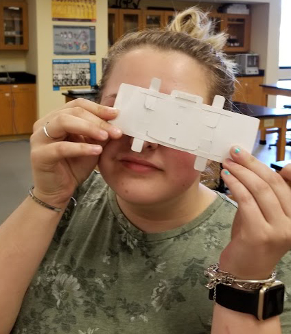 A student using the Foldscope to view a prepared slide. 