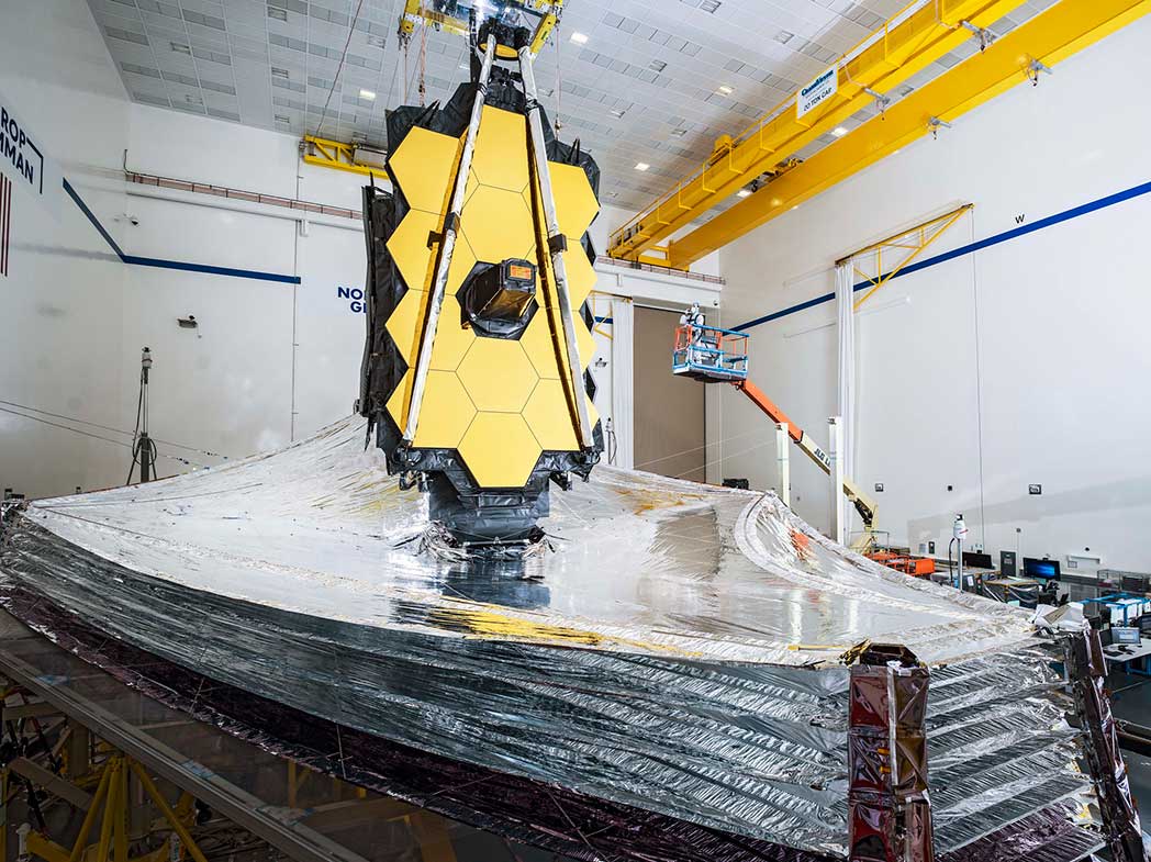 How does the JWST’s sunshield help maintain the operating temperature of the infrared instruments?