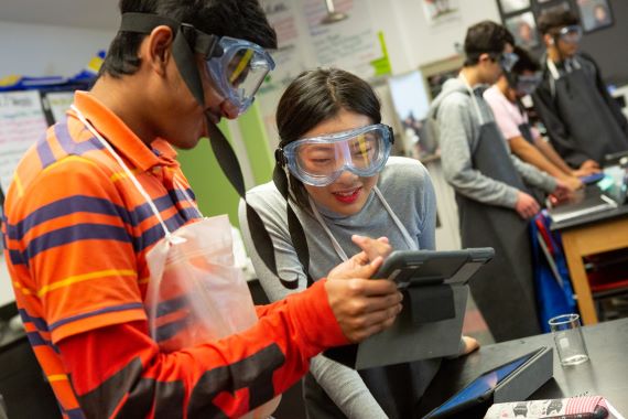 High school students read their lab directions on a computer tablet during AP chemistry class