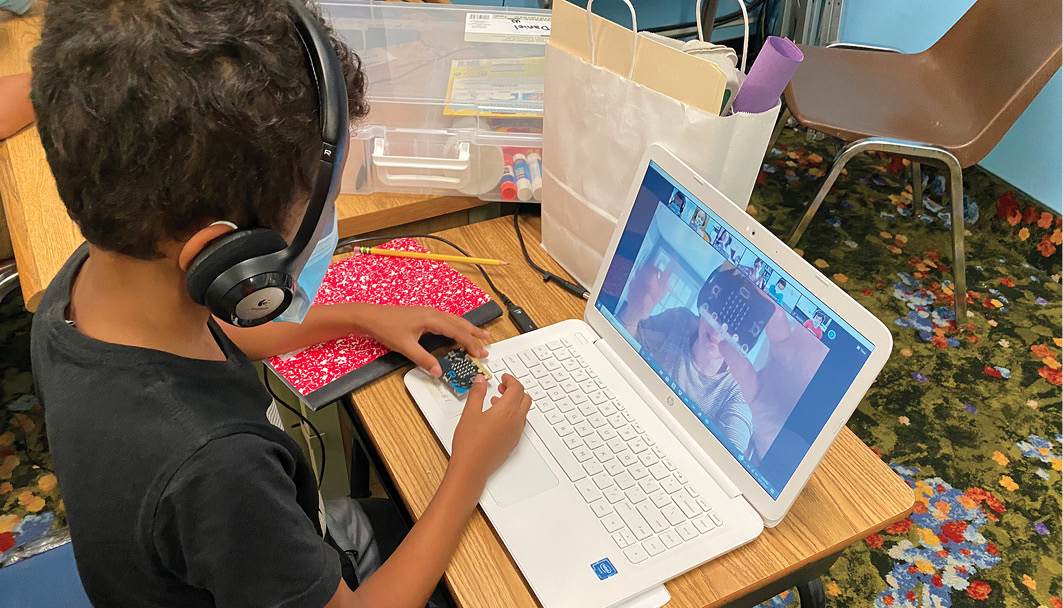 A student explores the components of a micro:bit while meeting with his group.