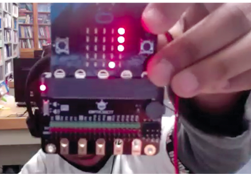 A child holds his successfully coded micro:bit for his teacher to see.