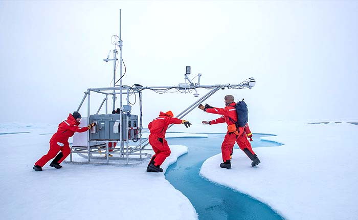 Scientists maneuver a “Flux Station,” a sled with instruments capable of measuring many atmospheric variables including temperature and radiation (incoming/outgoing), across the sea ice. Photo credit: Lianna Nixon