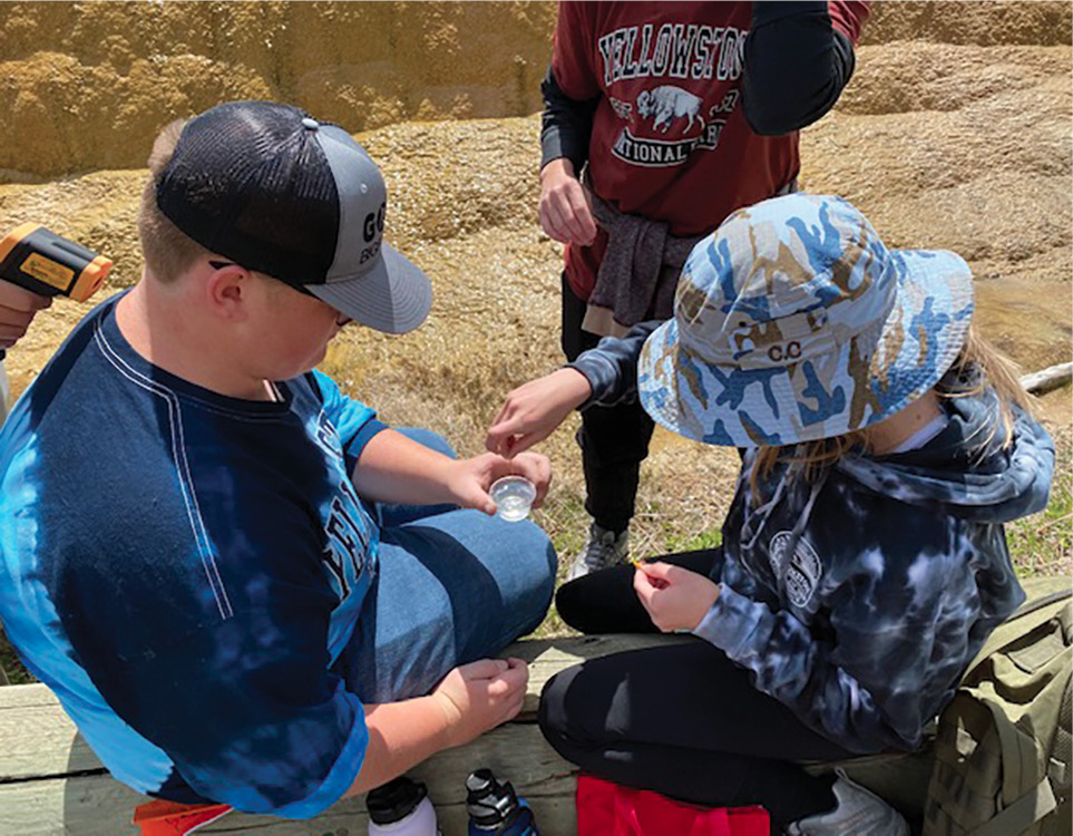 Figure 1 Students learn to use litmus paper to determine the pH of Orange Spring Mound’s water. This hot spring is located at Mammoth Hot Spring’s upper terrace.
