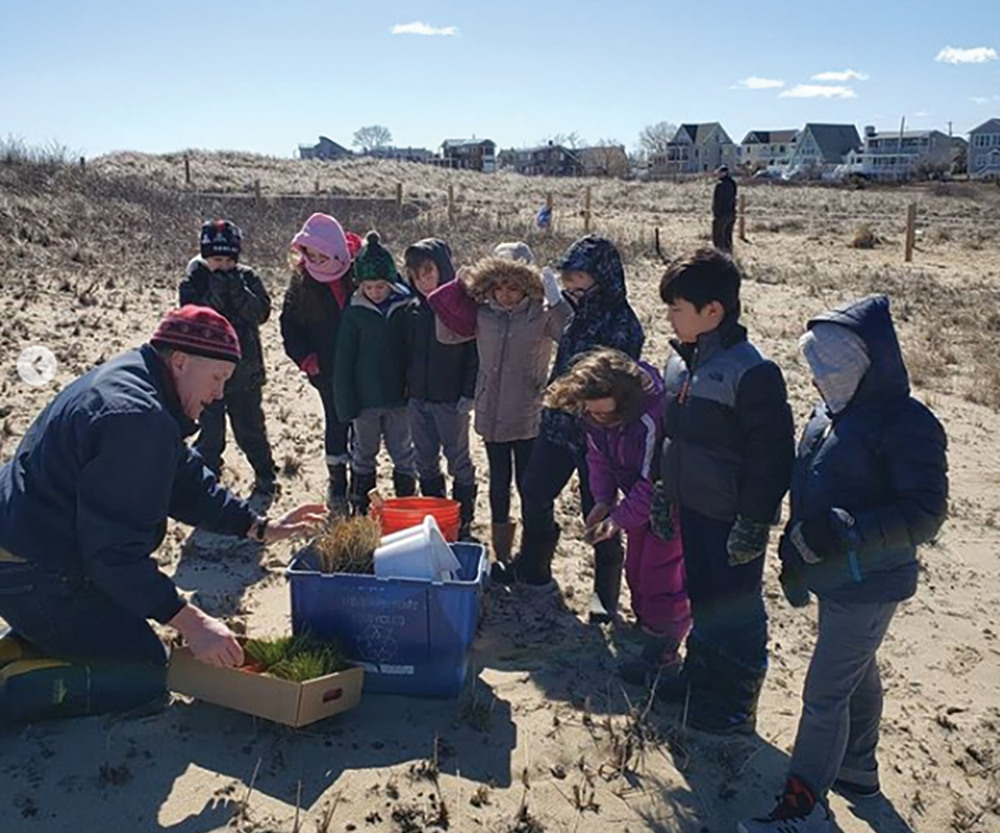 A volunteer instructs students on effective planting.