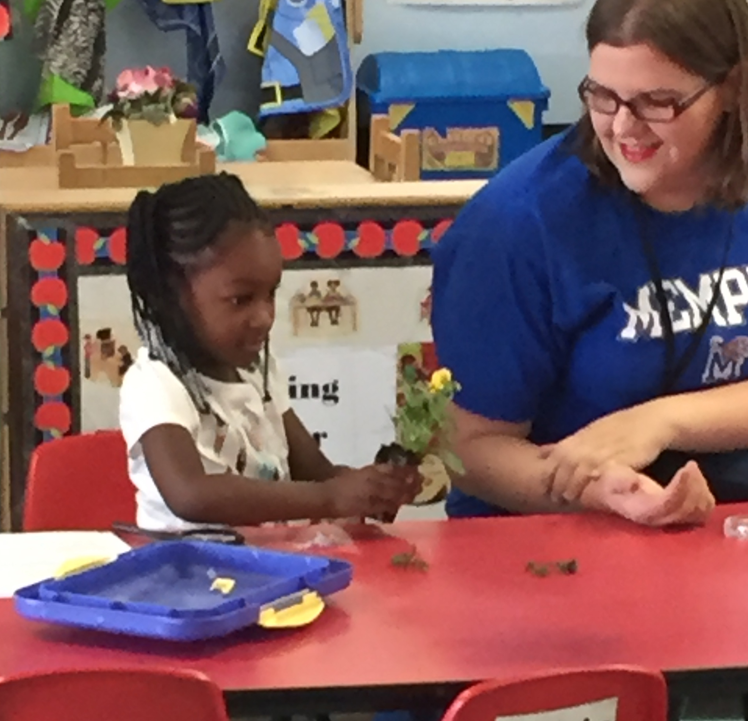 A girl practices using a watering can (left). The class discusses the parts of a plant (above).