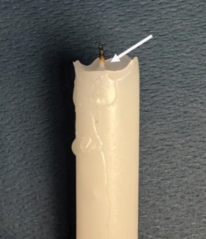 After burning, the bottom of a candle’s exposed wick remain unburnt (white arrow).
