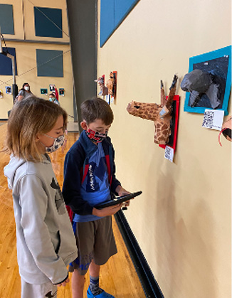 iPads in hand, students tour the Zooseum, listening to their peers’ presentations on animal adaptations.